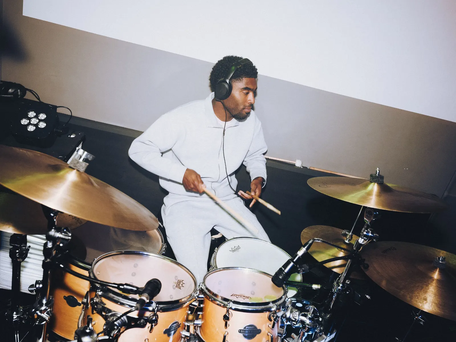 Drummer met koptelefoon achter het drumstel