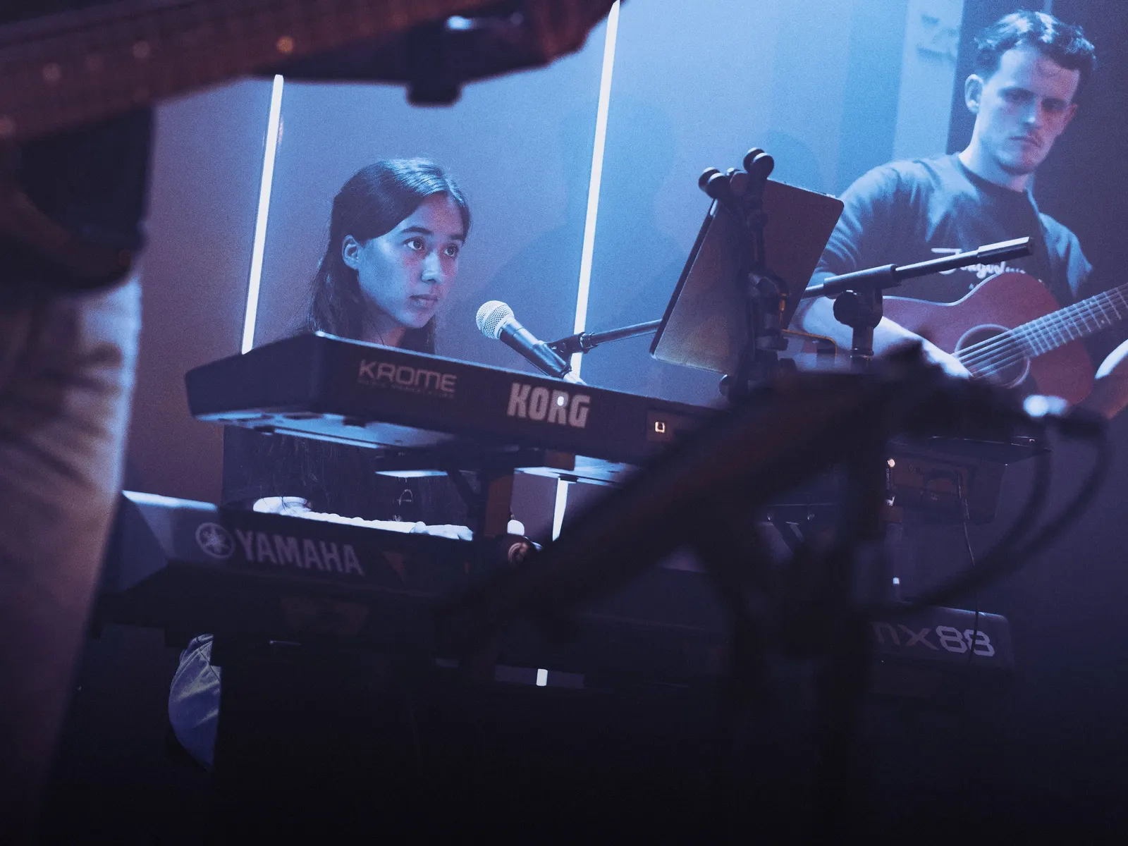 Toetsenist en gitarist tijdens het optreden in blauw licht