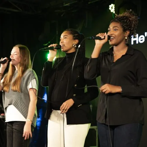 Drie zangeressen van Resonance zingen op het podium
